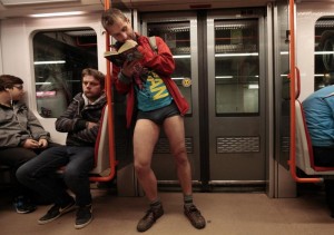 A passenger not wearing pants reads a book as he stands in a subway train during the "No Pants Subway Ride" in Prague