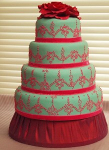 Four tier wedding cake with henna pattern and red flower topper